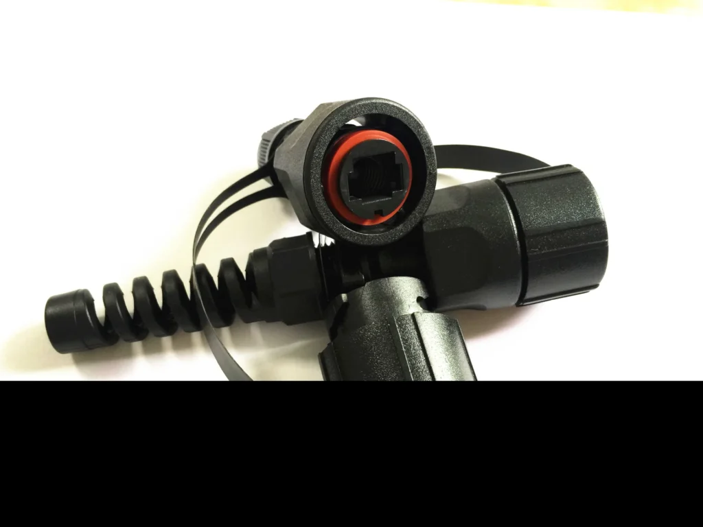 Close-up view of a rugged outdoor fiber connector showing the sealing gasket, coupling interface, and spiral strain-relief, designed for IP-rated FTTA/RRH applications.