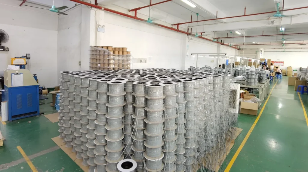 Factory production floor with bulk reels of pre-connectorized FTTH drop cable ready for assembly